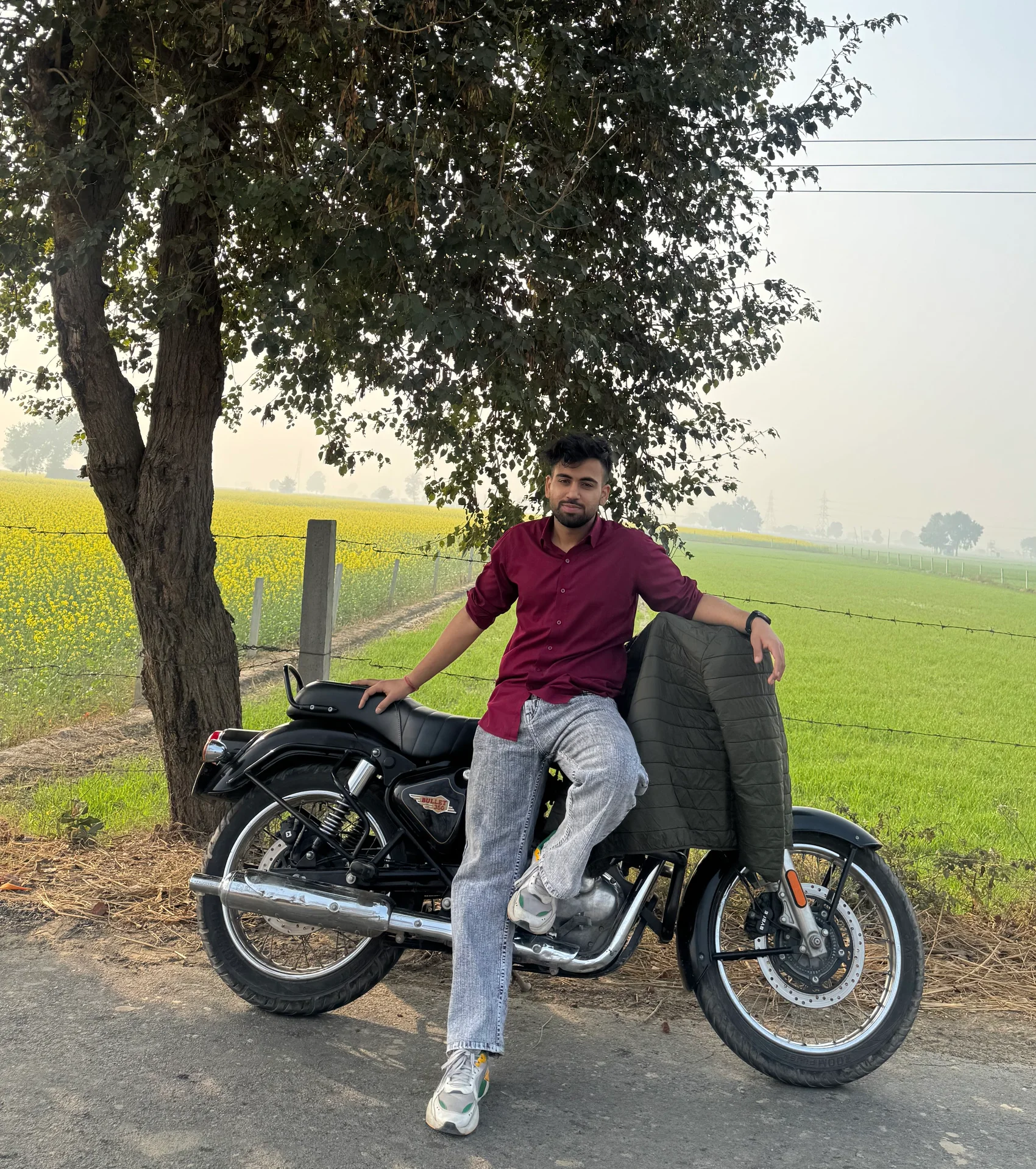 Ujjwal, founder of Shwane Luxe, with his motorcycle in a green field